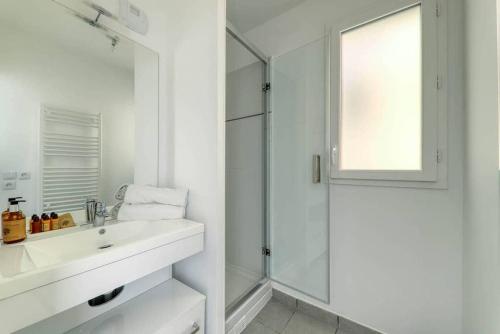 a white bathroom with a sink and a shower at Le duplex Disneyland Bmyguest in Montévrain