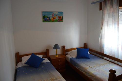 two twin beds in a bedroom with blue pillows at Casa Rosa in Monte Gordo