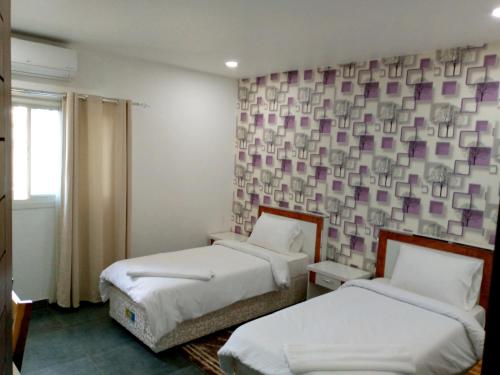 Zimmer mit 2 Betten und einer Wand mit lila Quadraten in der Unterkunft RESIDENCIAL AFRICA,LDA-NAMPULA in Nampula