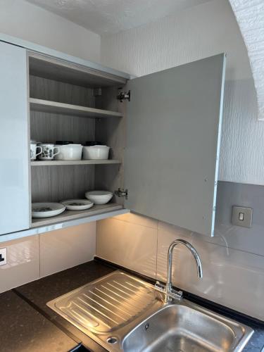 a kitchen with a sink and a shelf with dishes at The Pleasure 6&8 in Morecambe