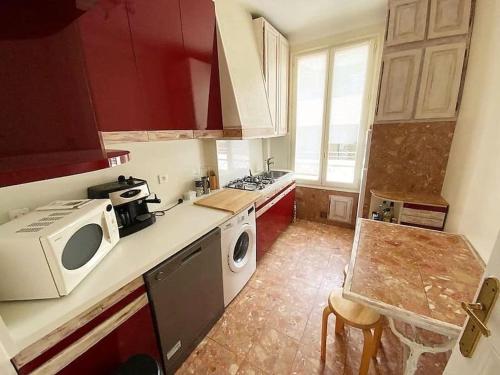 - une cuisine avec des placards rouges et un four micro-ondes blanc dans l'établissement C043-Agréable 3 Pièces proche Croisette et plages, à Cannes