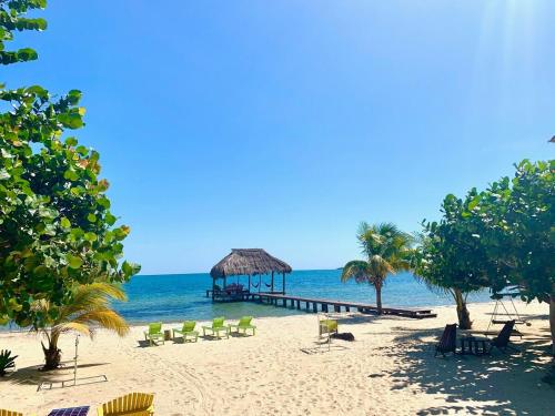 einen Strand mit Stühlen und einem Pavillon auf dem Wasser in der Unterkunft Seagrape Escape in Maya Beach