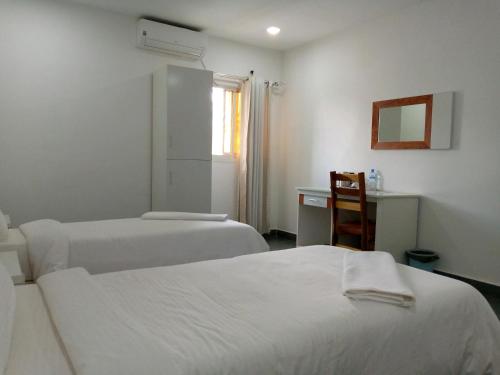 a room with two beds and a desk with a mirror at RESIDENCIAL AFRICA,LDA-NAMPULA in Nampula