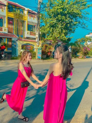 two women in red dresses are walking down the street at Hoi An Village Villa in Hoi An