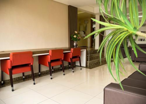 a waiting room with red chairs and a counter at Tri Hotel Xanxerê in Xanxerê