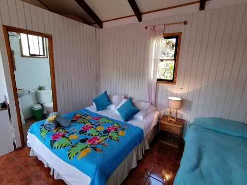 a bedroom with a bed with a blue blanket at Tuava Lodge in Hanga Roa