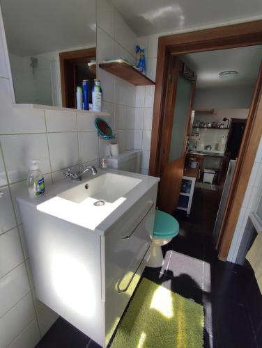 een badkamer met een witte wastafel en een spiegel bij Het Boetje in Lagoa