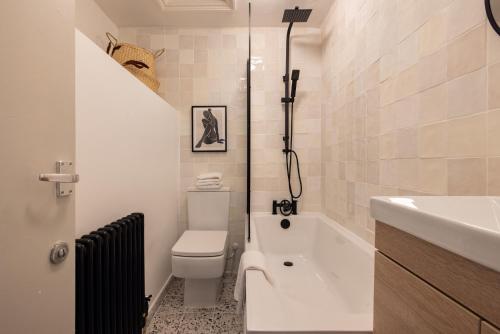 Baño blanco con aseo y lavamanos en The Kensington And Chelsea Classic - Glamorous 2BDR Flat en Londres
