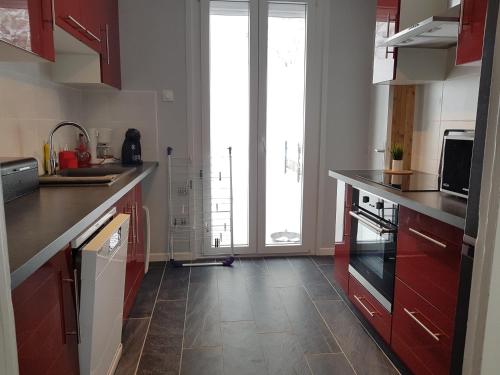 une cuisine avec des armoires rouges et une grande fenêtre dans l'établissement MONETTE 1, à Le Mont-Dore