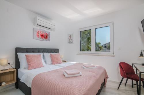 een slaapkamer met een bed met roze kussens erop bij Modern Apartments Elle Malinska in Vantačići