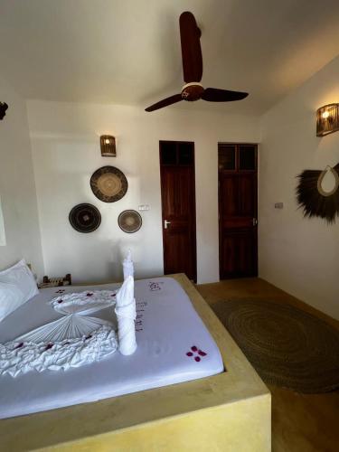 a bedroom with a bed with a ceiling fan at Equalia Rose Hotel in Jambiani