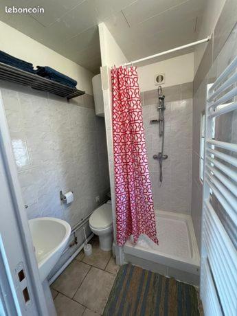 une salle de bain avec toilettes et rideau de douche dans l'établissement Le Tricorne, à Saint-Vaast-la-Hougue