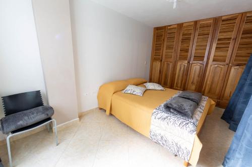 a small bedroom with a bed and a chair at Apartamentos Primavera in Jardin