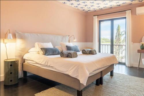 um quarto com uma cama com duas almofadas em Colorful Villa with pool by OTYNA AM em Estoril