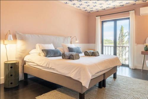una camera da letto con un letto con due cuscini sopra di Colorful Villa with pool by OTYNA AM a Estoril