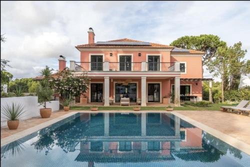 a home with a swimming pool in front of a house at Colorful Villa with pool by OTYNA AM in Estoril