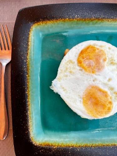 een gebakken ei op een groen bord met een vork bij Equalia boutique hotel in Jambiani