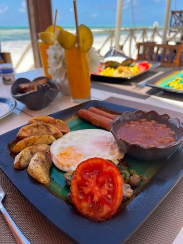 een blauw bord met eten, een ei en tomaten bij Equalia boutique hotel in Jambiani