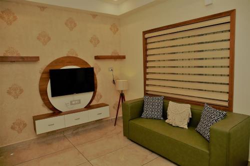 a living room with a green couch and a tv at AGS Residency in Ernakulam