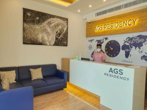 a person standing at a reception desk with a clock at AGS Residency in Ernakulam