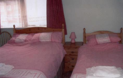 ブリドリントンにあるSpa Holiday Apartmentsのピンクのシーツとランプが備わるベッドルームのベッド2台