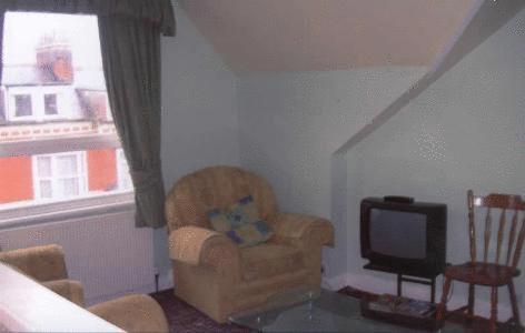 a living room with a chair and a television at Spa Holiday Apartments in Bridlington