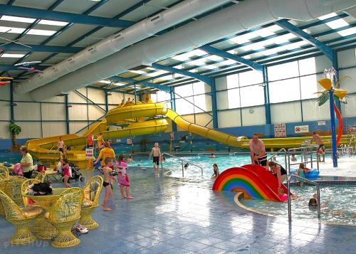 a group of people playing in a water park at TM18 - 3 Bedroom Mobile Home Golden Palms Resort TV`s in Every Room Decking Indoor Heated Pool Entertainment complex & Close To Beaches PASSES NOT INCLUDED in Skegness