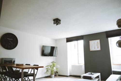 a living room with a table and a clock on the wall at Le DrômArdèchois - Gîte meublé 6 personnes Tournon sur Rhône - ÉCOLODGÎTE in Tournon-sur-Rhône