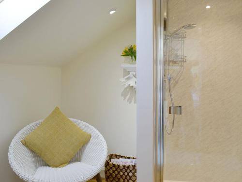 uma cadeira de vime branca com uma almofada amarela na casa de banho em West Wood Hideaway em Middleton