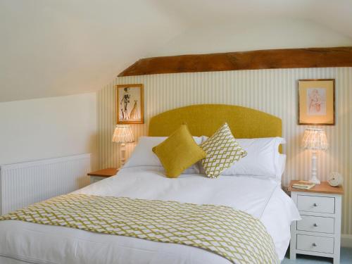 um quarto com uma grande cama branca com almofadas amarelas em West Wood Hideaway em Middleton
