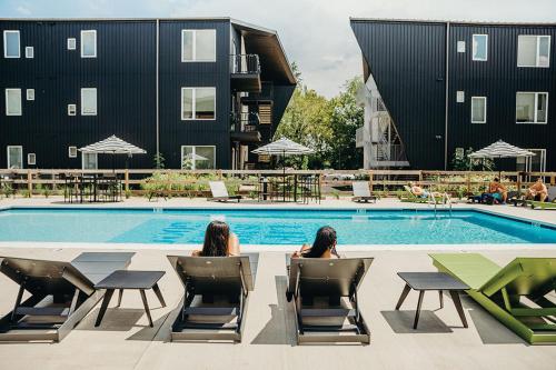two women sitting in chairs in front of a swimming pool at Sleepover 1BD 1BA Downtown Bowling Green Apartments in Bowling Green