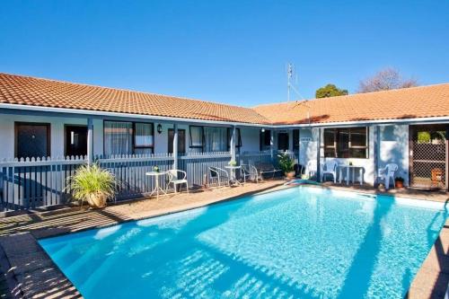 a swimming pool in front of a house at Cortez Motel in Whakatane