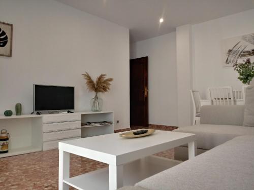 a white living room with a white table and a tv at Balcón del Cardenal in Baeza