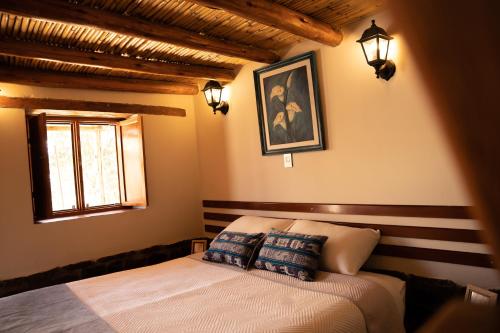 a bedroom with a bed with two pillows and a window at Lodge El Portal de Qopuy in Coporaque