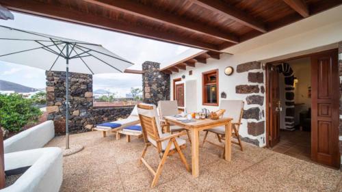 a patio with a table and chairs and an umbrella at Casa Margarita 4 in Mala
