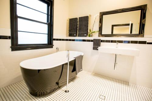 a bathroom with a tub, toilet, sink and mirror at The Commercial Boutique Hotel in Tenterfield