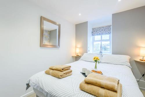 a bedroom with a white bed with towels and a mirror at Awel Y Mor Sea Breeze in Cemaes Bay