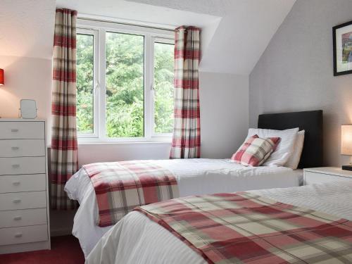 a bedroom with two beds and a window at The Penthouse in Bowness-on-Windermere