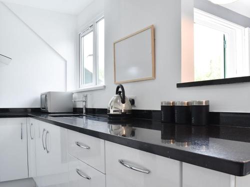 a kitchen with white cabinets and black counter tops at The Penthouse in Bowness-on-Windermere
