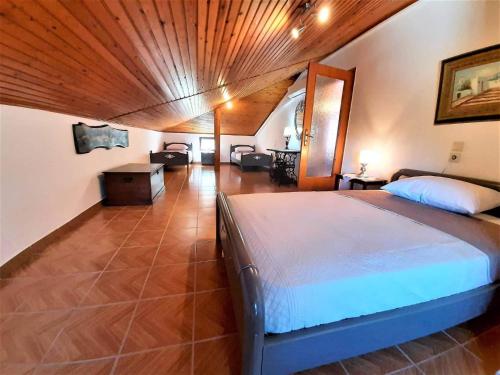 een slaapkamer met een groot bed en een houten plafond bij ARCHONTISSA Lagonisi villa in Kalívia Thorikoú