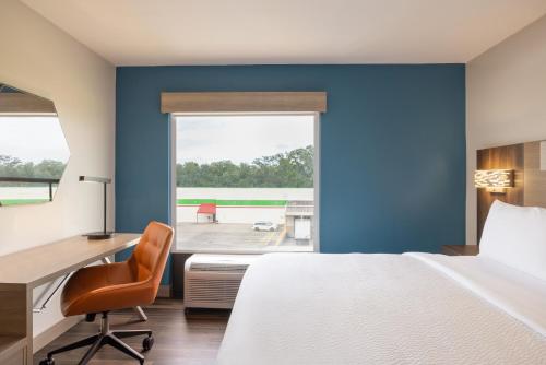 a bedroom with a bed and a desk and a window at Holiday Inn Express & Suites Opelousas by IHG in Opelousas