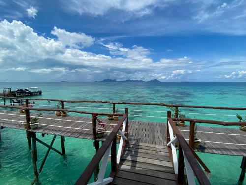 a wooden bridge over the water with a view of the ocean at Pavalintang Resort in Semporna