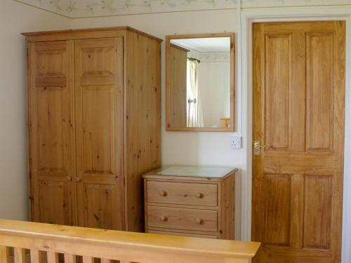 a room with a wooden cabinet and a mirror at The Shippon in Lympsham