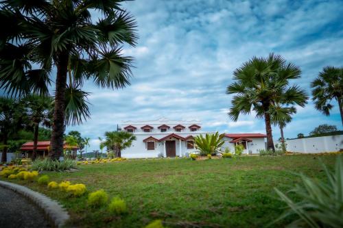 a white house with palm trees and a road at Kathircholai in Trincomalee