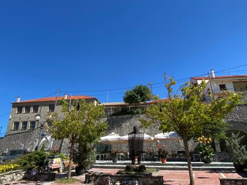 a patio with trees and umbrellas in front of a building at Sofia’s House in Pramanta