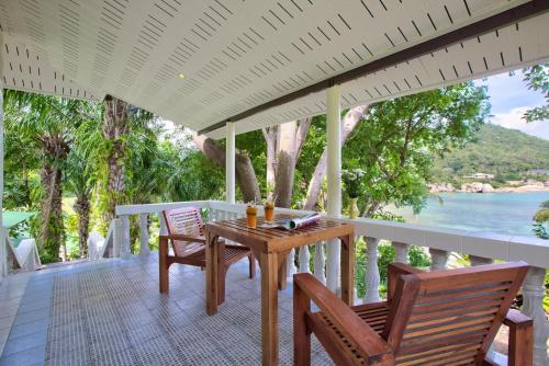 a wooden table and chairs on a porch with a view of the water at Crystal Bay Yacht Club Beach Resort in Lamai