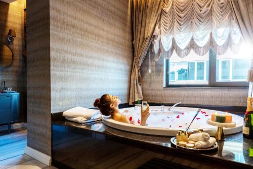 Una donna sdraiata in una vasca da bagno in una stanza di Hotel De Reve Galata-Special Class a Istanbul