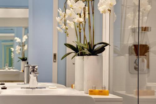 La salle de bains est pourvue d'un lavabo et d'un vase avec des fleurs blanches. dans l'établissement Walkers Arms Hotel, à Adélaïde