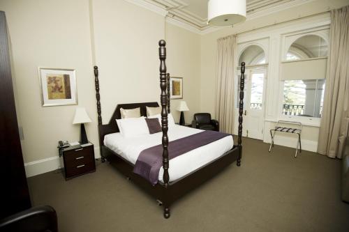 a bedroom with a four poster bed in a room at Largs Pier Hotel in Adelaide