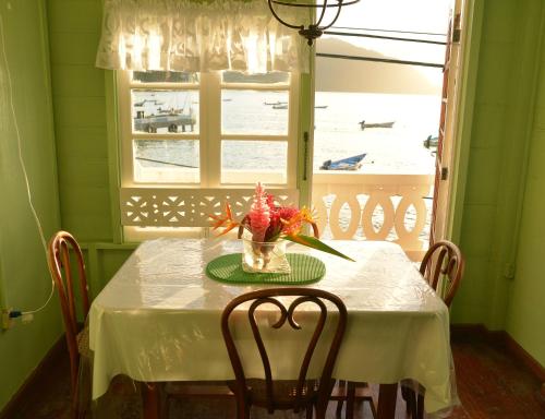 a table with a vase of flowers and a window at Cholson Chalets in Charlotteville